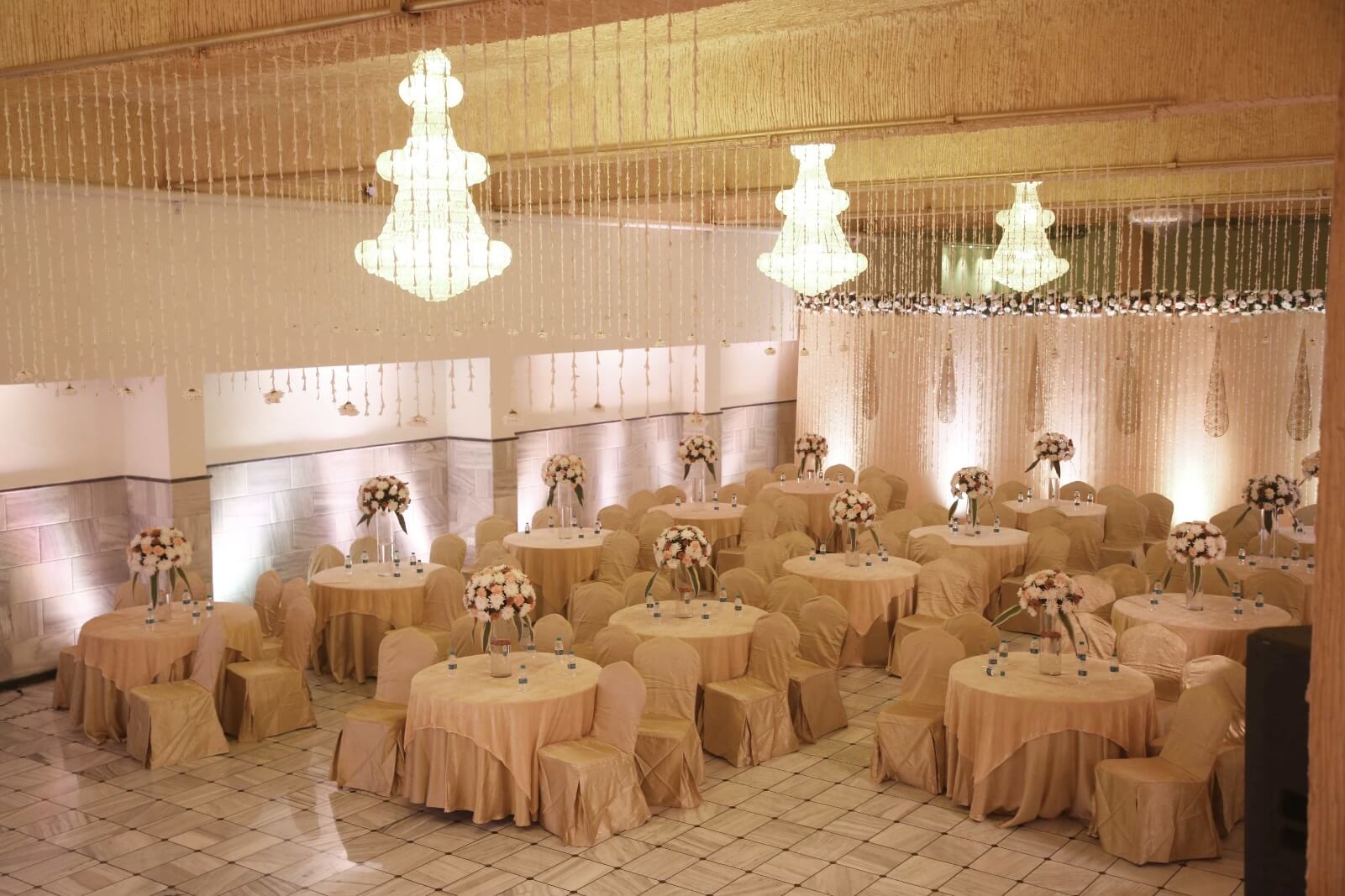 Elegant wedding banquet hall at EllBee Ganga View, Rishikesh, featuring beautifully arranged round tables with floral centerpieces and ambient lighting